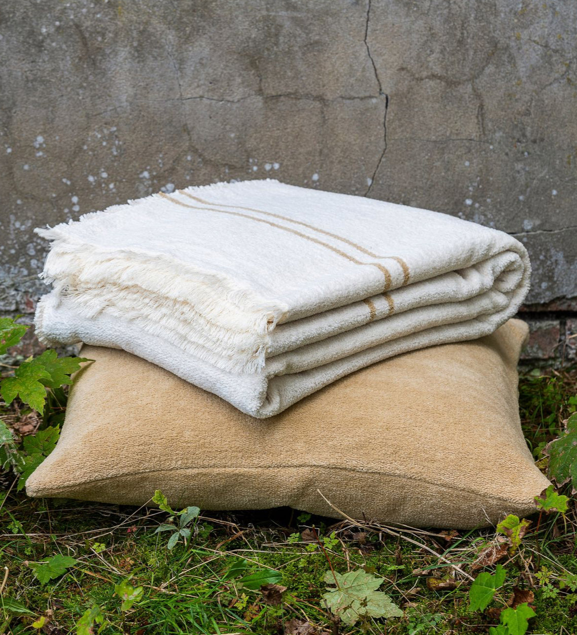 Scapa Home throw  'Piuma' in off white with camel colour band on camel cushion