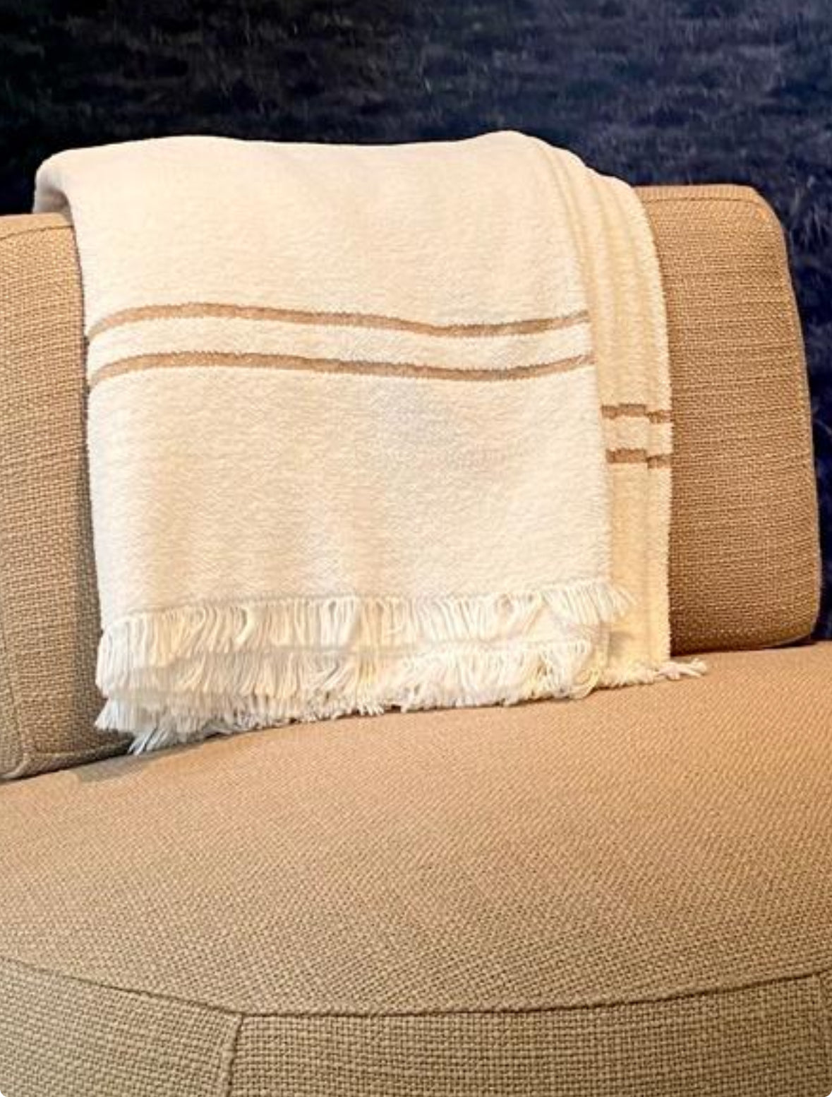Scapa Home throw 'Piuma' in off white with camel coloured band on armchair 'Pebble'